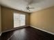 This bedroom features beautiful dark floors, neutral walls, a ceiling fan, and a sun-filled window at 675 Paper Creek Dr, Lawrenceville, GA 30046