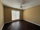 This bedroom features beautiful dark floors, neutral walls, a ceiling fan, and a sun-filled window at 675 Paper Creek Dr, Lawrenceville, GA 30046