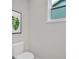 Simple powder room with a white toilet, light gray walls and a small window and a framed piece of art at 53 Colonial Ter, Villa Rica, GA 30180