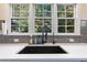Close up of a kitchen sink with updated hardware and a view out a set of windows to the greenery outside at 1203 Bonshaw Trl, Marietta, GA 30064