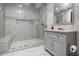 Elegant bathroom featuring marble walls, herringbone floor, glass shower with bench, and a gray vanity with marble countertop at 490 Revenna Trl, Fayetteville, GA 30214