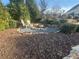 Outdoor firepit area with stone pavers, two chairs, and surrounded by mature trees and shrubs at 77 Russell Rd, Lawrenceville, GA 30043