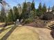 Landscaped backyard featuring a stone walkway, chairs, mature trees, and attractive stone walls at 77 Russell Rd, Lawrenceville, GA 30043