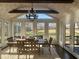 Sunroom dining area with vaulted ceiling, rustic chandelier, large windows, and scenic backyard views at 77 Russell Rd, Lawrenceville, GA 30043