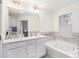 Bright bathroom with double vanity, large mirror, soaking tub and neutral tile accents at 7652 Baron Rd, Fairburn, GA 30213