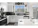 Bright kitchen featuring white cabinets, quartz countertops, stainless steel appliances, and view from window at 7652 Baron Rd, Fairburn, GA 30213