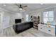 An open living room with hardwood floors, black couch, TV and lots of windows at 10683 Glenleigh Dr, Johns Creek, GA 30097