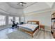 Spacious main bedroom featuring a tray ceiling, three large windows, and a modern ceiling fan at 10683 Glenleigh Dr, Johns Creek, GA 30097