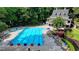 Aerial view of a sparkling blue pool with lounge chairs, umbrellas, and a clubhouse surrounded by mature trees at 10683 Glenleigh Dr, Johns Creek, GA 30097