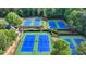 Overhead view of several well-maintained tennis courts surrounded by lush greenery at 10683 Glenleigh Dr, Johns Creek, GA 30097