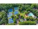 Aerial view showcasing tennis courts, pool, playground, and parking area surrounded by mature trees at 10683 Glenleigh Dr, Johns Creek, GA 30097