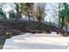 Picturesque backyard featuring a concrete patio, brick accents, tiered landscaping, and serene surroundings at 160 Deer Cliff Cv, Lawrenceville, GA 30043