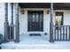 Covered front porch of a two-story brick home with black front door and pillars at 160 Deer Cliff Cv, Lawrenceville, GA 30043