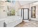 Luxurious main bathroom with a soaking tub, glass-enclosed shower, and a large window at 160 Deer Cliff Cv, Lawrenceville, GA 30043