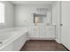 Bright bathroom featuring double vanity, large mirror, and a tiled tub, providing a relaxing space at 2845 White Blossom Ln, Suwanee, GA 30024