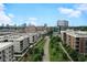 An aerial view of apartment homes with lush green spaces, walking paths, and a beautiful city skyline at 567 Ponce De Leon Ne Ave # 502, Atlanta, GA 30308