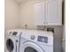 This is a Laundry room featuring a washer and dryer and overhead white cabinets at 305 Hembree Grove Trce, Roswell, GA 30076