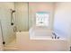 Bathroom showcasing white tiles, a glass shower and a soaking tub with a window view at 3187 Moor View Rd # 37, Duluth, GA 30096