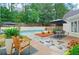 Backyard pool surrounded by mature trees, greenery, a stone path, and an outdoor dining area at 500 River Bluff Pkwy, Roswell, GA 30075