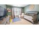 Cozy, sage green room featuring a crib, toy shelves, and comfortable glider chair at 2880 Ridge Manor Dr, Dacula, GA 30019