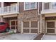 Exterior view of the garage doors of townhome with brick facade and well-maintained landscaping at 142 Perimeter Walk, Atlanta, GA 30338
