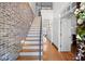 Bright foyer featuring a wooden staircase with a brick accent wall and hardwood flooring at 1605 Ridenour Nw Pkwy, Kennesaw, GA 30152