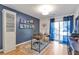 Bright home office featuring a large desk, wood floors, blue accent wall, and sliding glass doors to the back patio at 1115 Riverbend Club Se Dr, Atlanta, GA 30339