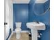 Blue half-bath features pedestal sink, round mirror, and tile flooring at 1146 Sims Sw St, Atlanta, GA 30310