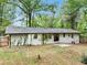 Back exterior of home showing white painted brick, mature vines, and fenced yard at 5626 Noblett Sw Rd, Stone Mountain, GA 30087