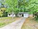 Cozy single-story home with white paint, black trim, and mature trees in a lush yard at 5626 Noblett Sw Rd, Stone Mountain, GA 30087