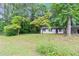 Cozy single-story home with white paint, black trim, and mature trees in a lush front yard at 5626 Noblett Sw Rd, Stone Mountain, GA 30087