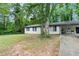 Charming single-story home with white paint, black trim, and mature shade trees in a lush yard at 5626 Noblett Sw Rd, Stone Mountain, GA 30087