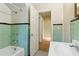 Bathroom featuring a green tiled wall, bathtub, and a white sink with an open doorway to another room at 1815 Monroe Ne Dr, Atlanta, GA 30324