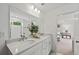 Bright bathroom featuring double sinks, quartz counters, large mirror, and an open doorway to the bedroom at 628 Topsail Drive Pkwy, Villa Rica, GA 30180