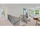 Bright, neutral hallway featuring a modern railing and a glimpse into a naturally lit, comfortable lounge area at 628 Topsail Drive Pkwy, Villa Rica, GA 30180