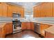Well-equipped kitchen boasts wooden cabinets, stainless appliances, granite countertops, and subway tile backsplash at 325 Morning Mist Walk, Suwanee, GA 30024