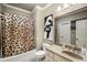 Well-lit bathroom with a shower featuring a unique animal print curtain, single vanity, and decorative mirror at 415 Prestwick Ct, Alpharetta, GA 30005