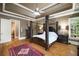 Spacious main bedroom featuring a four poster bed, tray ceilings, hardwood floors, and bright natural light at 415 Prestwick Ct, Alpharetta, GA 30005