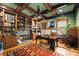 Home office featuring wood-paneled walls, coffered ceiling, fireplace, built-in bookshelves, and hardwood floors at 415 Prestwick Ct, Alpharetta, GA 30005