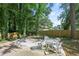 Outdoor patio area with a round table and chairs surrounded by lush trees and a wooden fence at 971 Clover Ln, Lawrenceville, GA 30044