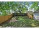 View of a backyard featuring a wooden fence, an upward sloping grassy lawn, and mature trees at 971 Clover Ln, Lawrenceville, GA 30044