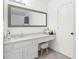 Bright bathroom featuring a large mirror, granite countertop, white cabinets, and a cozy vanity stool at 971 Clover Ln, Lawrenceville, GA 30044