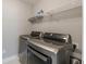 Modern laundry room featuring stainless steel, front-loading LG washer and dryer, with overhead shelving at 1703 Prospect Way, Conyers, GA 30094