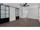 A modern bedroom with barn doors, ceiling fan, and dark wood flooring at 3850 Crosby Nw Dr, Atlanta, GA 30331