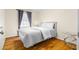 Bedroom with hardwood floors, white bedding, and a window with patterned curtains at 147 Windy Hill Sw Rd, Marietta, GA 30060