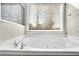 Close up of bright white bathtub with chrome hardware and a view to the backyard through the window at 4198 Haynes Mill Nw Ct, Kennesaw, GA 30144