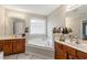 Bathroom featuring dual vanities, a soaking tub, a frosted window, and modern lighting fixtures at 2524 Oakleaf Rdg, Lithonia, GA 30058