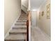 Carpeted staircase featuring a wooden handrail and white trim provides access to the upper levels of the home at 2524 Oakleaf Rdg, Lithonia, GA 30058