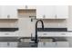 Close up on the sleek, dark faucet and undermounted sink with dark countertops and white cabinets at 30 Sportsman Path, Dallas, GA 30157