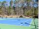 Bright blue tennis court surrounded by tall trees, perfect for recreational activities at 3405 Lake Valley Way, Douglasville, GA 30135